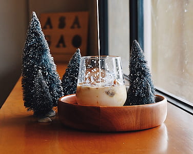 clear glass on brown wooden bowl beside four pine tree decors thumbnail