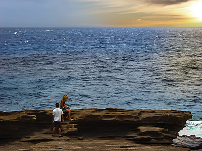 man and woman sitting on rock near body of water thumbnail