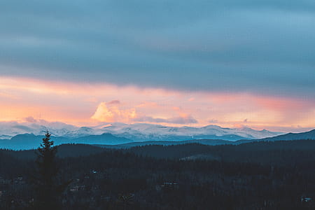 skyline photography of mountain with trees under cloudy sky thumbnail