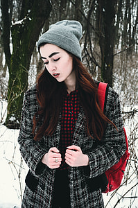 woman in grey beanie standing on snow covered ground during daytime thumbnail