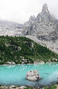 body of water near mountain during daytime thumbnail