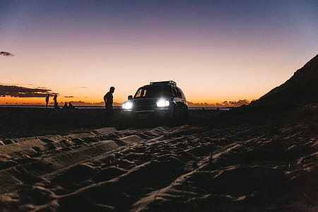 silhouette of man standing beside SUV thumbnail
