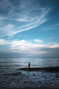 topless man holding boat paddle in body of water thumbnail