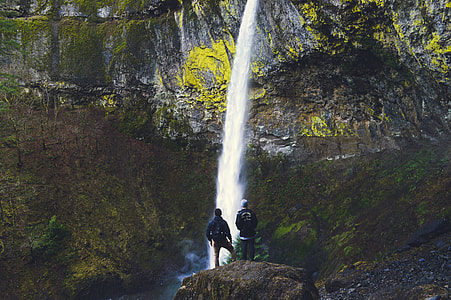 two men standing on rock in front of waterfalls thumbnail