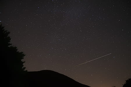 silhouette of mountain under shooting star at night time thumbnail