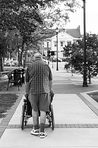 grayscale photo of man pushing wheelchair thumbnail