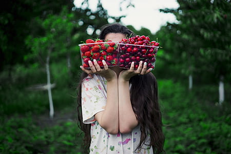 woman holding clear plastic containers filled with strawberries and cherries outdoor during daytime thumbnail