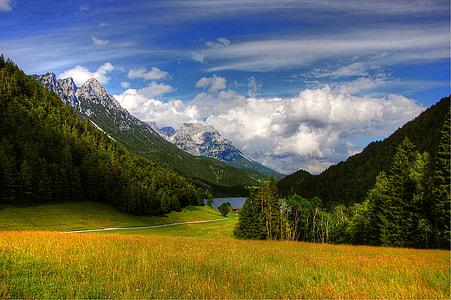 photo of green grass field across green mountains and body of water during daytime thumbnail