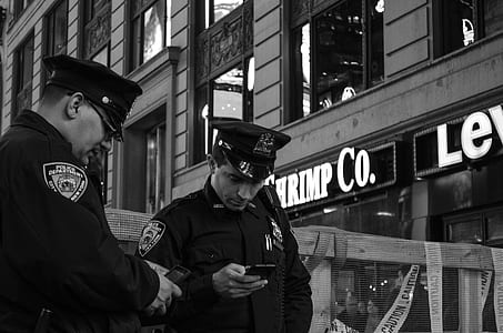 two cops holding phones near building thumbnail
