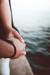 two people holding hands near body of water thumbnail