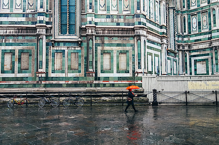 person using orange umbrella walking in the street thumbnail