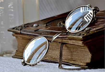 close-up photography of gold-colored frame eyeglasses on top of brown book thumbnail