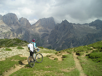 person holding full-suspension bike on top of mountain under white clouds during daytime thumbnail