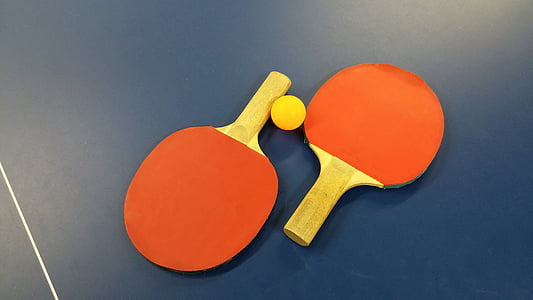 pair of red-and-brown ping-pong paddles on blue surface with yellow ping-pong ball thumbnail