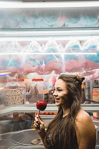 woman holding candied apple near store thumbnail