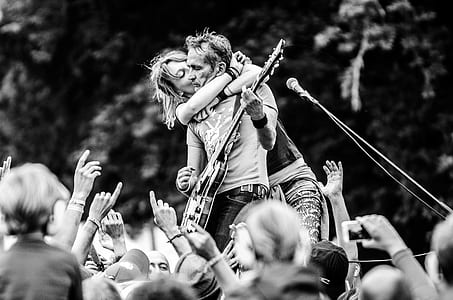 Grayscale Photo of a Woman Kissing a Man Playing Guitar thumbnail