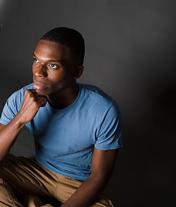 man left hand on chin sitting near wall thumbnail