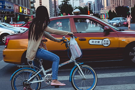 woman riding on bike beside red and yellow taxi during daytime thumbnail