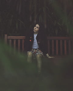 woman sitting on wooden bench near trees thumbnail