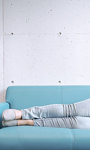 person wearing gray skinny jeans and slip on shoes on a sky-blue couch thumbnail