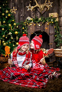 two girls in red-white-and-black fair isle ear-flap hat and scarfs holding lollipops thumbnail