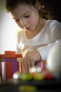girl in white long-sleeved shirt playing toy thumbnail
