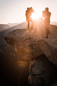 two men standing on boulder taking photo thumbnail