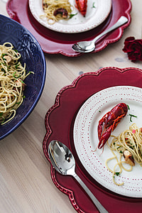 Fancy dinner with seafood pasta, crayfish and red wine by the table decorated with roses thumbnail