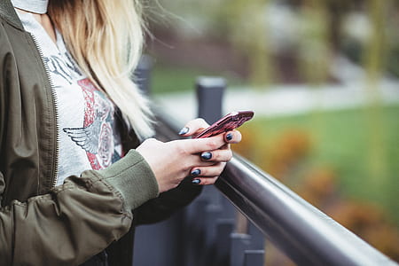 woman wearing green full-zip jacket using red smartphone thumbnail