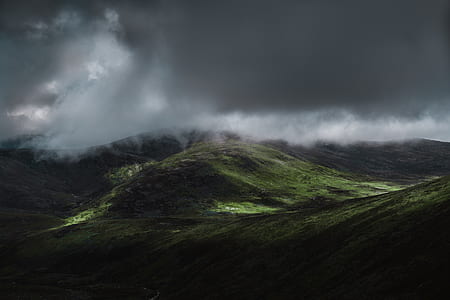 landscape photography of hill under gloomy clouds thumbnail