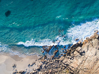 bird's-eye view photography of body of water crushing on shore thumbnail