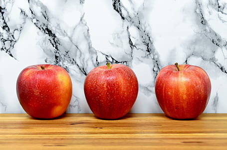 three red apples on brown wooden surface thumbnail