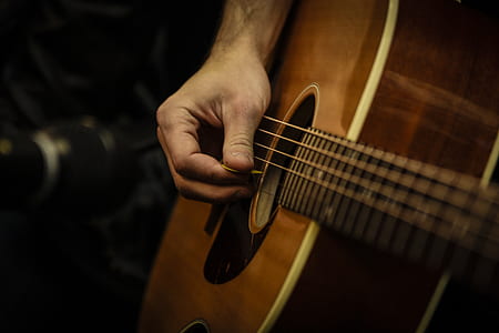 photo of person holding using pick on guitar thumbnail