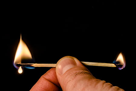 person holding two lighted safety matches sticks thumbnail