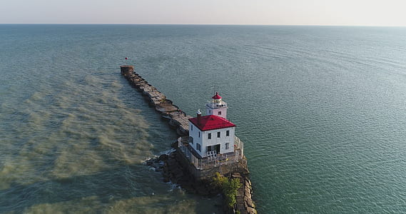 white and red house on cliff surrounded with water at daytime thumbnail