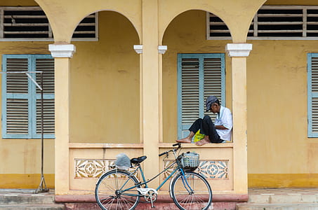 man sitting near bicycle during daytime thumbnail