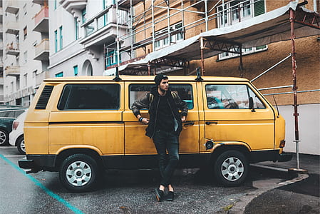 person leaning on yellow minivan parked near building thumbnail