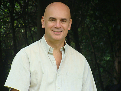 smiling man in white button-up T-shirt near trees thumbnail