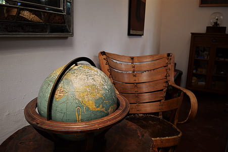 globe with brown wooden base on top of brown table beside brown armchair thumbnail