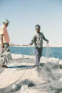 man holding fish net near man standing during daytime thumbnail