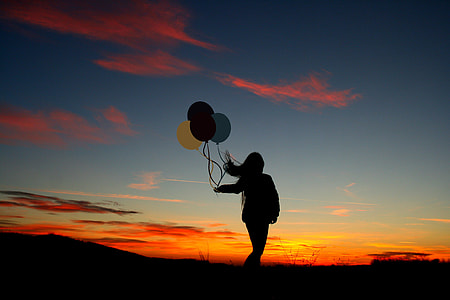 silhouette photo of woman holding a balloons thumbnail