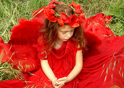 girl wearing red sleeveless scoop-neck dress while sitting on green grass thumbnail
