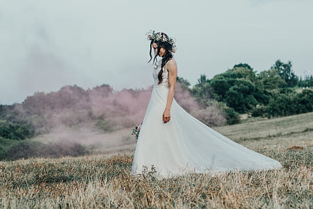 woman standing on grass field wearing wedding gown thumbnail