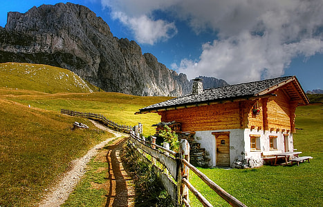 brown wooden house near mountain at cloudy sky thumbnail