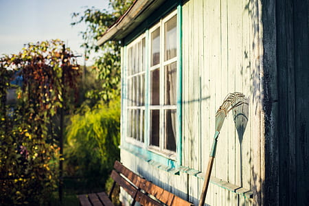 blue and brown garden rake leaning on white wooden wall during daytime thumbnail
