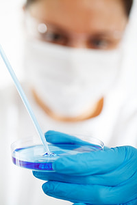 close up photography of person in blue laboratory gloves holding round clear case with blue liquid thumbnail