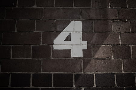 white 4 print on brown brick wall thumbnail