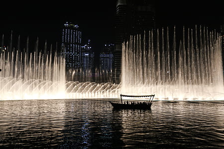 Silhouette of a Boat on a Body of Water With Fountain thumbnail
