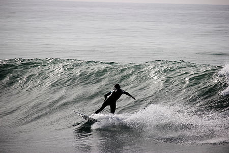 grayscale photography of person riding surfboard on barrel waves thumbnail