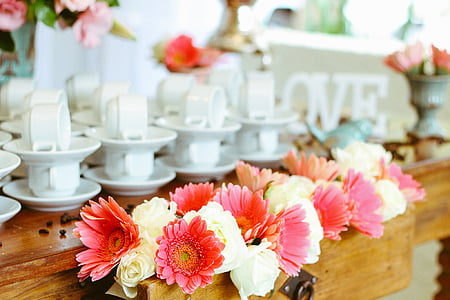 white roses and pink daisies arrangement in drawer chest of table with white ceramic teacups thumbnail